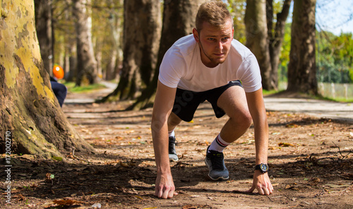 Before the start,Young sports man in start position preparing to run