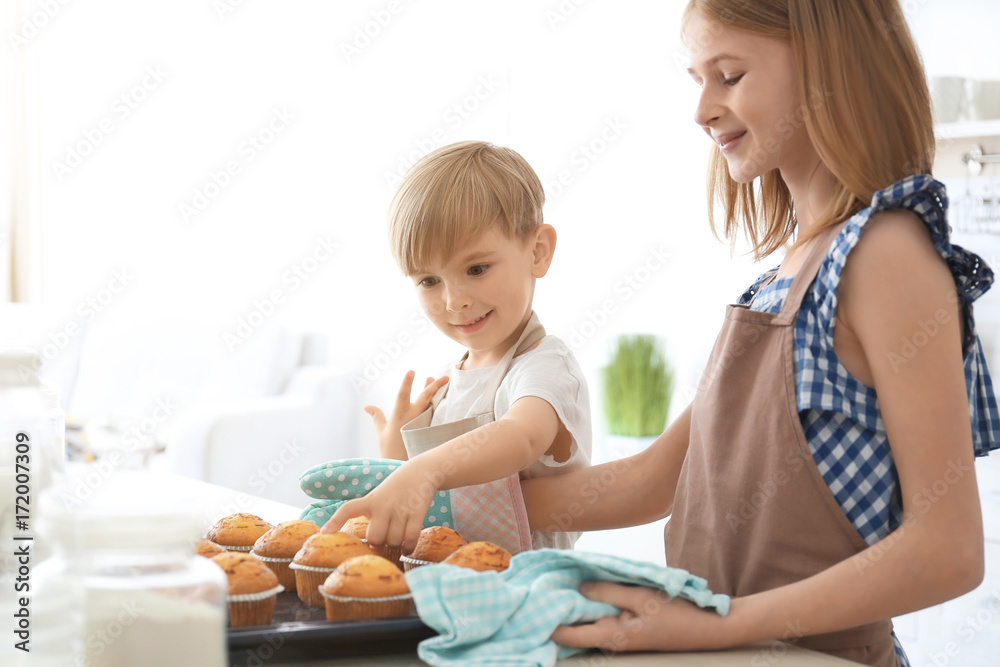 Boy and girl with muffins in kitchen. Cooking classes concept Boy and girl with muffins in kitchen. Cooking classes concept