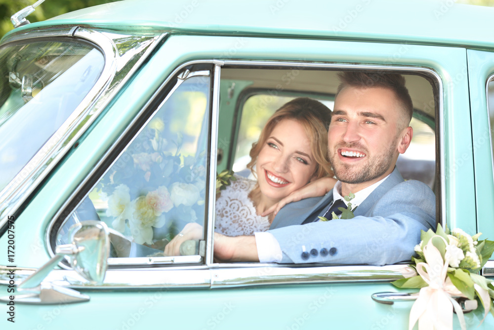 Happy wedding couple in car