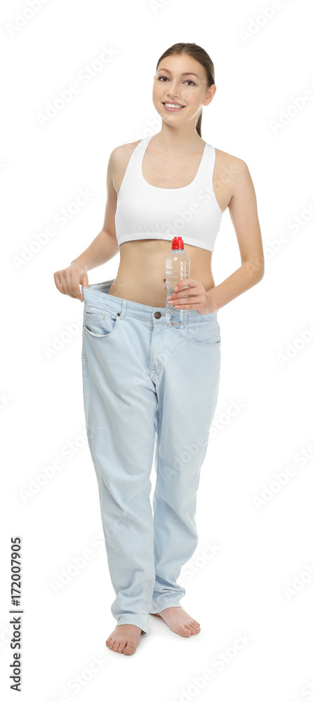 Beautiful young woman in oversized jeans with bottle of water on white background. Diet concept Beautiful young woman in oversized jeans with bottle of water on white background. Diet concept