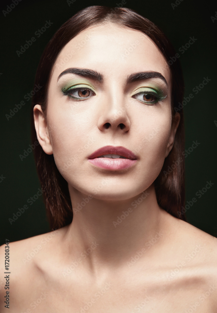 Young beautiful woman with fancy green makeup on dark background Young beautiful woman with fancy green makeup on dark background