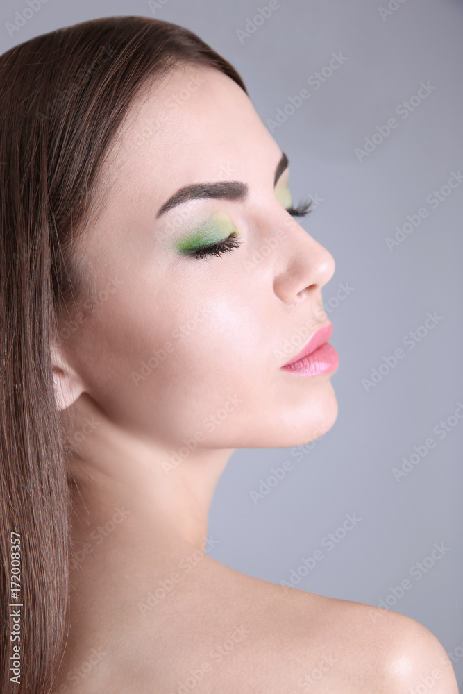 Young beautiful woman with fancy green makeup on grey background Young beautiful woman with fancy green makeup on grey background