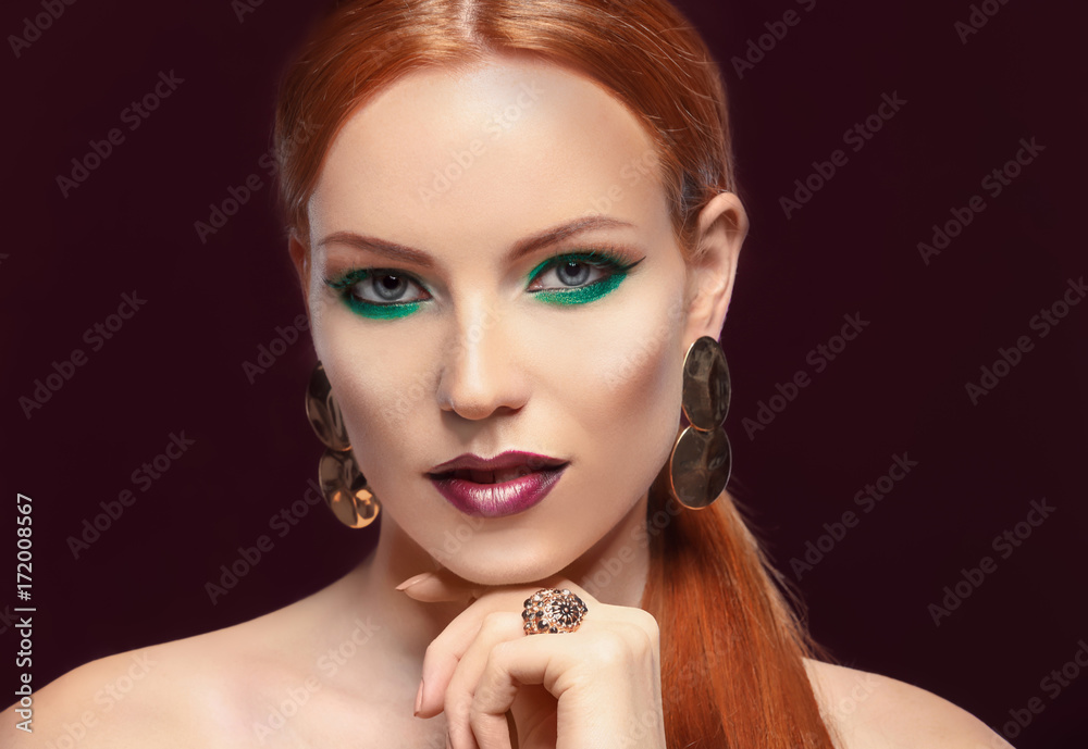 Fototapeta premium Beautiful redhead woman with bright green makeup on dark background