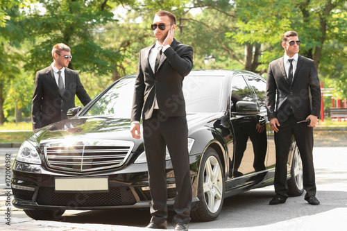Handsome bodyguards near car outdoors photo