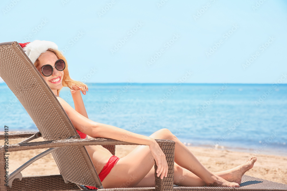 Young woman in Santa hat on beach. Christmas holidays concept