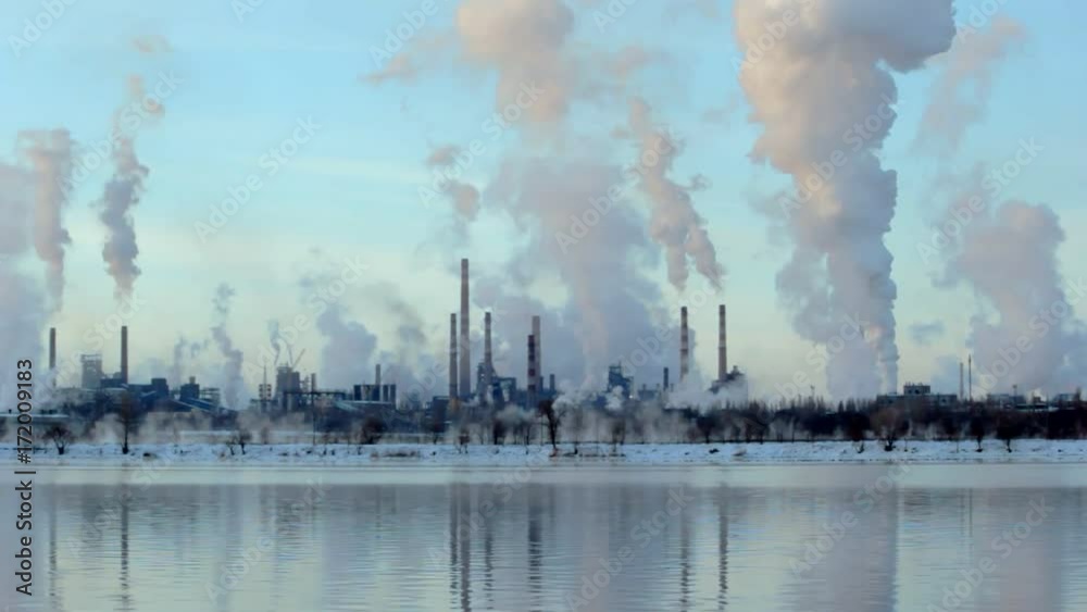 The reflection of a large smokestack factory in the river, industrial pipe The reflection of a large smokestack factory in the river, industrial pipe