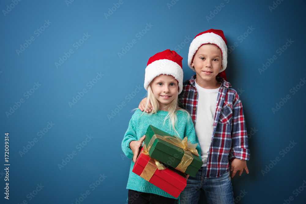 Cute little children with Christmas presents on color background Cute little children with Christmas presents on color background