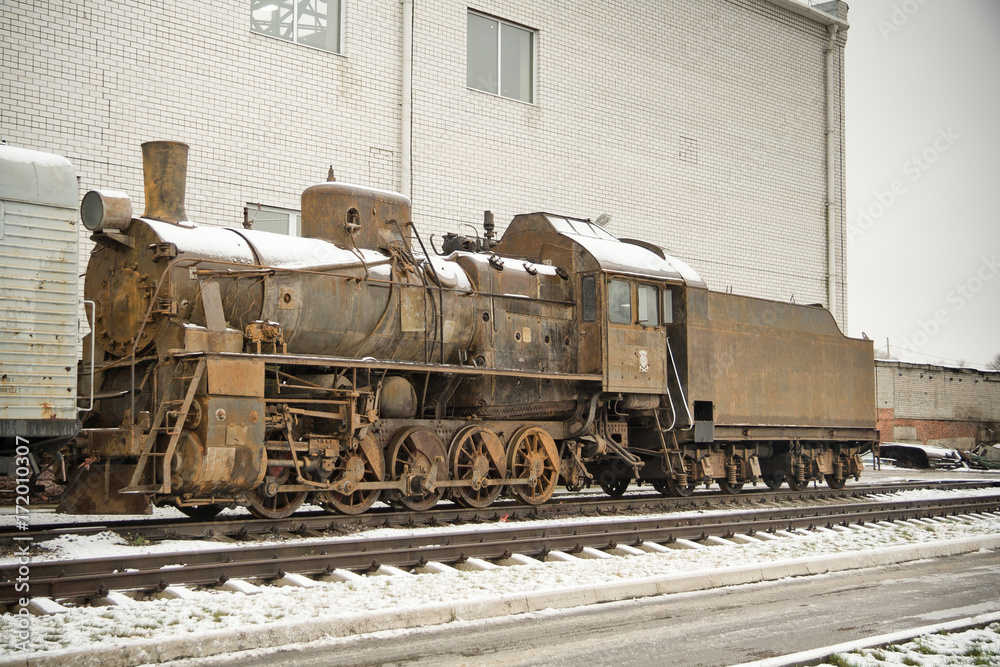 Old rusty steam engine on railroad in winter