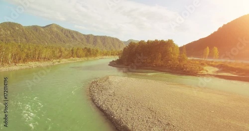 4k (UHD) aerial view. Low flight over fresh cold mountain river at cloudy summer morning. Green trees and sun rays on horisont. Fast horizontal movement