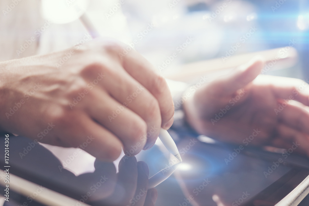 Naklejka premium Closeup view of man holding digital tablet on hand and using electronic pen while working at sunny office.Pointing tablet screen.Blurred background.Horizontal.Visual effects.