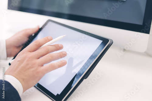 Closeup view of two male hands holding electronic tablet and touching screen.Businessman working at office.Horizontal.Blurred background.