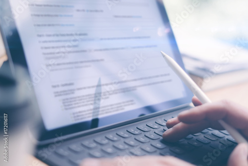 Blogger using mobile touchpad and stylus pen for work.Male hands typing electronic tablet keyboard-dock station.Horizontal, blurred background.