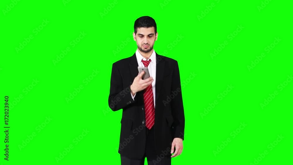 Caucasian businessman talking on cell phone in the studio while wearing formal suit in front of green screen background Caucasian businessman talking on cell phone in the studio while wearing formal suit in front of green screen background