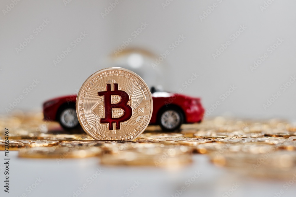 Bitcoin coin near red car Bitcoin coin near red car