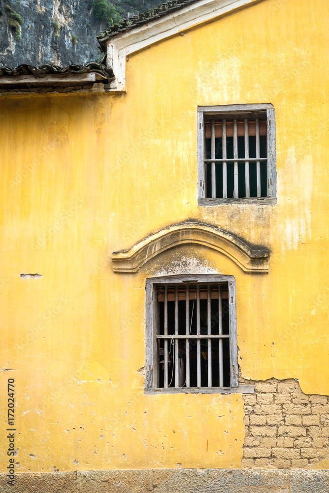 The old wooden window on yellow ancient brick wall