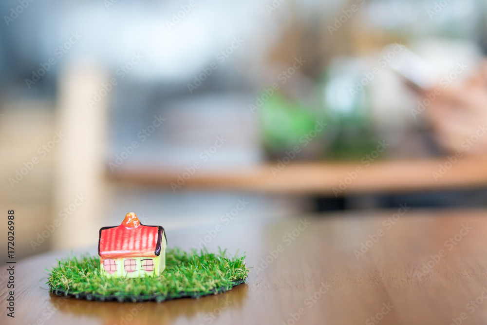miniature ceramic house on wooden mock up over blurred green garden on day noon light. Image for property real estate investment concept. miniature ceramic house on wooden mock up over blurred green garden on day noon light. Image for property real estate investment concept.