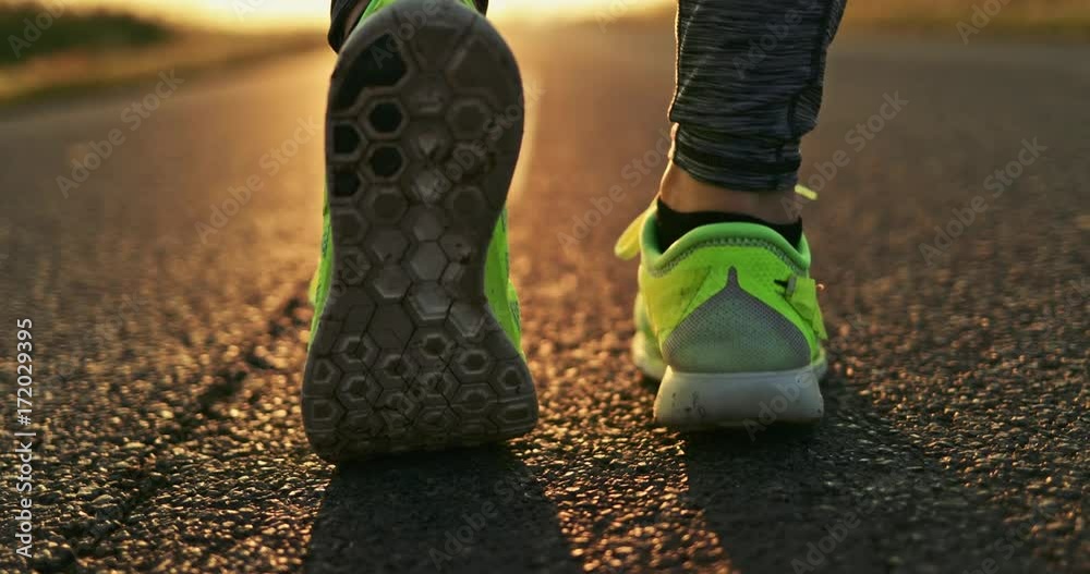 Woman Running on a Countryside Road at Sunrise. SLOW MOTION 4K DCi. Female jogger athlete training at dusk. Active healthy lifestyle concept. Cinematic sports shot. 