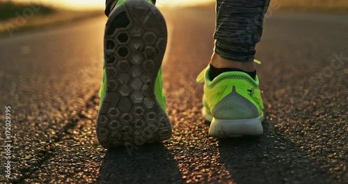 Woman Running on a Countryside Road at Sunrise. SLOW MOTION 4K DCi. Female jogger athlete training at dusk. Active healthy lifestyle concept. Cinematic sports shot. 