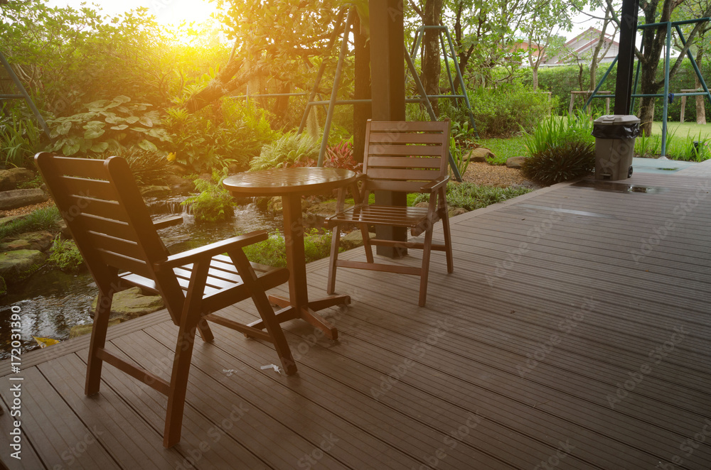 Table and wooden chairs are placed on the wooden floor in the garden of the morning.