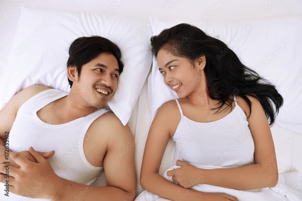 Romantic asian couple lying down and looking each other Romantic asian couple lying down and looking each other