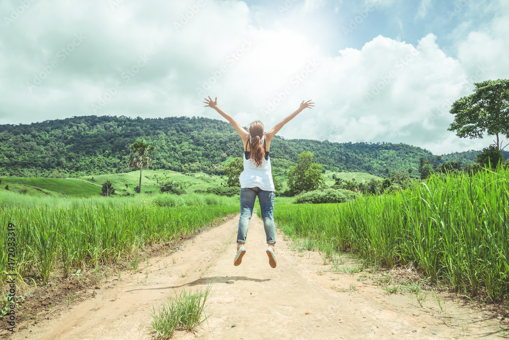 Asian women travel relax in the holiday. Running jumping on the middle of the meadow road