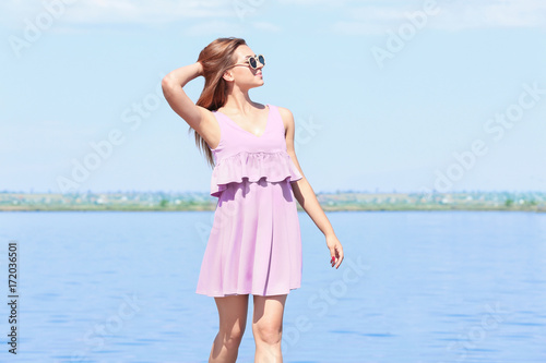 Beautiful young woman on embankment in sunny day
