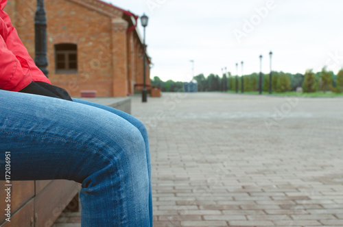 Young woman sits on the bench in the city park alley. Resting people.
