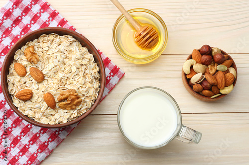 healthy breakfast. oatmeal, milk, honey and nuts on white wooden table. Top view with copy space