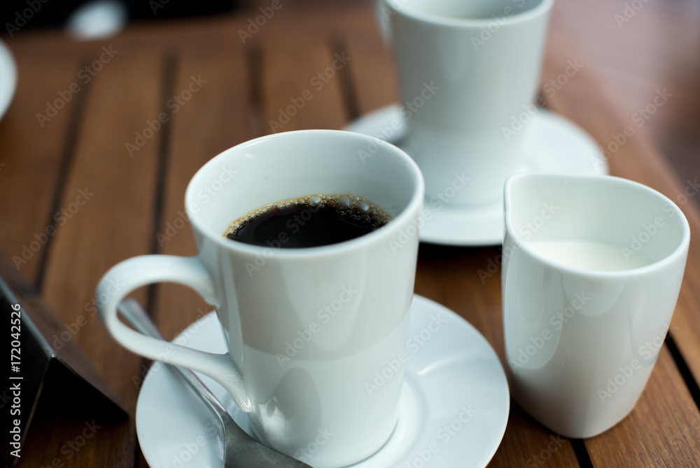A cup of black coffee and mug of milk A cup of black coffee and mug of milk