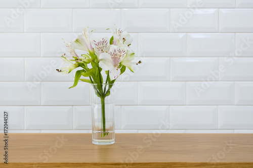 bunch flower in a vase on wooden table with white wall texture background.
