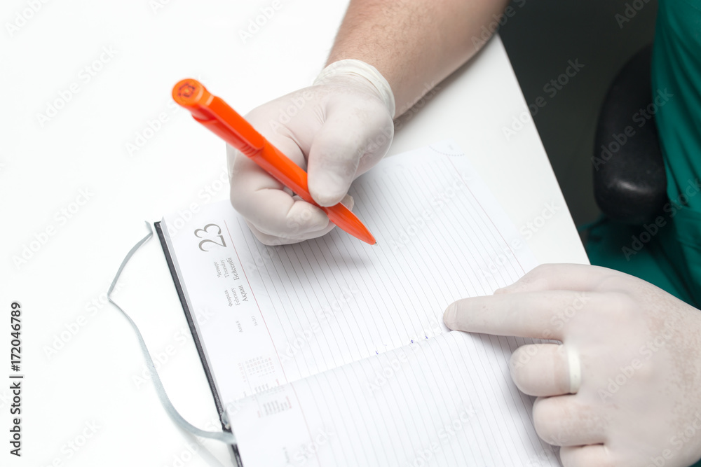 The doctor writes in a notebook at the clinic The doctor writes in a notebook at the clinic