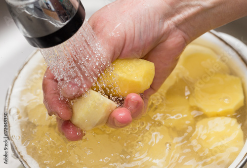 The cook washes the peeled potatoes in the water