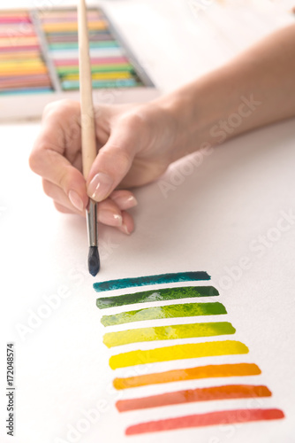 Artist painting colorful stripes with brush on white paper