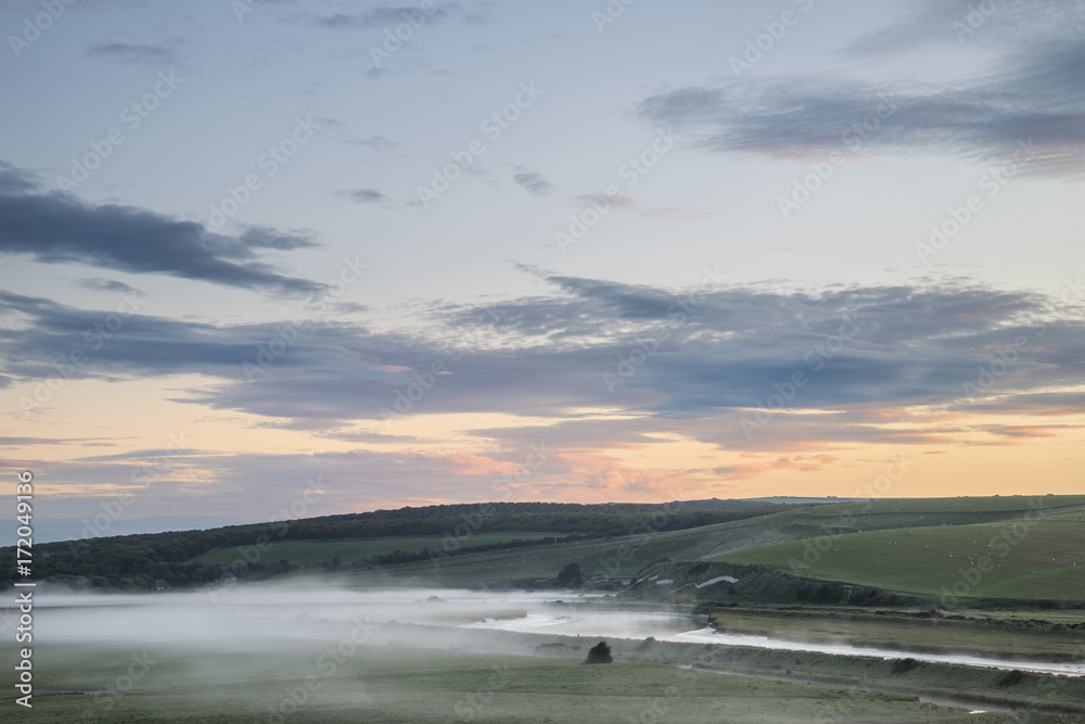 Beautiful dawn landscape over English countryside with river slowly flowing through fields Beautiful dawn landscape over English countryside with river slowly flowing through fields