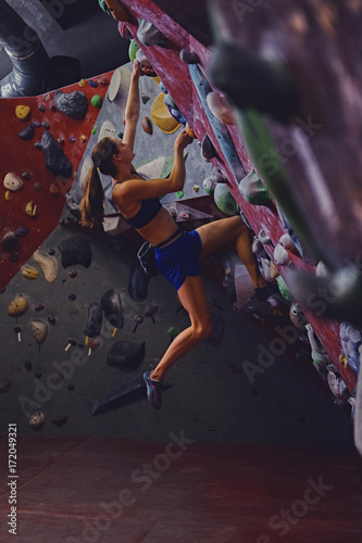 Professional female climber on a bouldering wall.