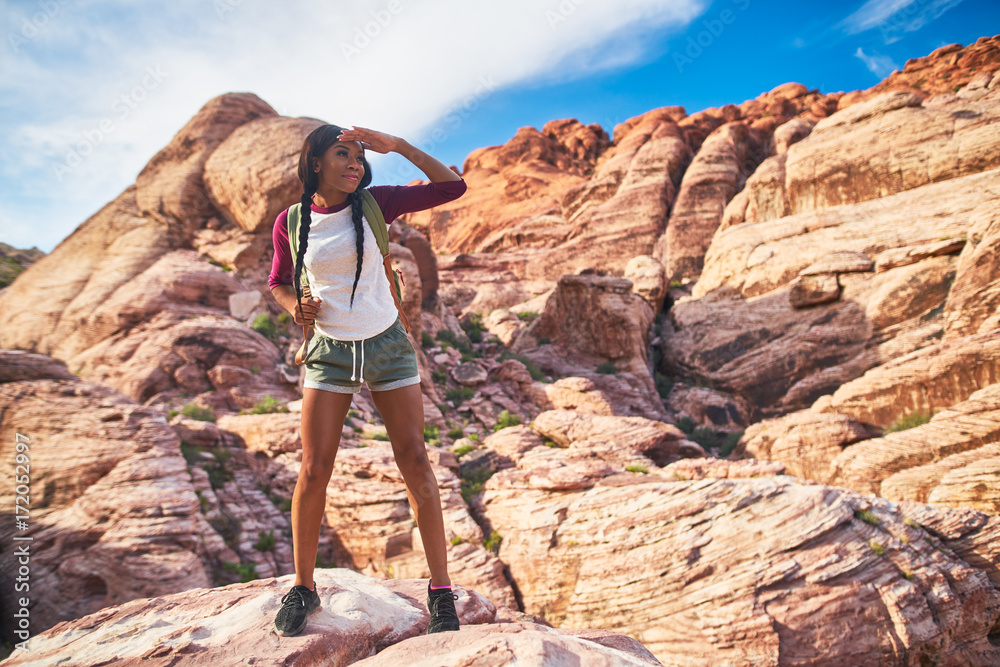 athletic african american woman standing on cliff edge at red rock canyon park looking at landscape