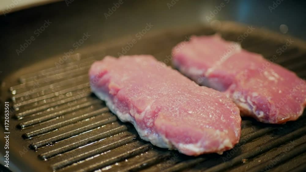 Raw meat on hot grill pan are frying in slow motion. Food concept and