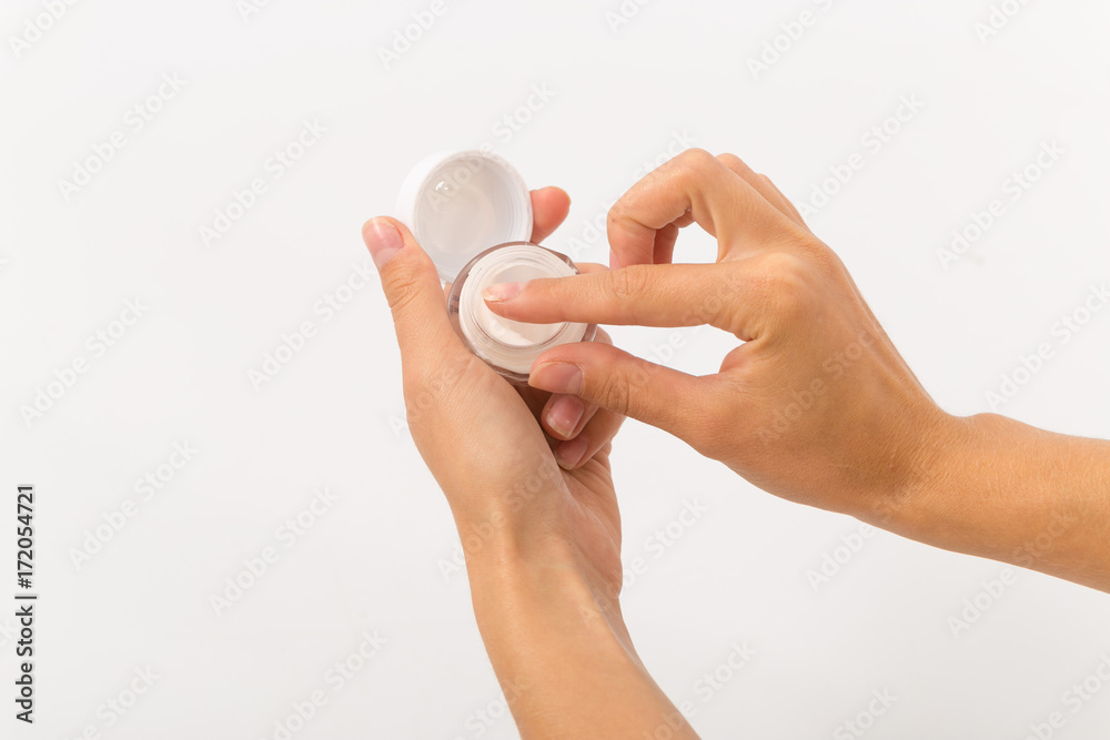 white cream in a small glass jar in female hands. white cream in a small glass jar in female hands.