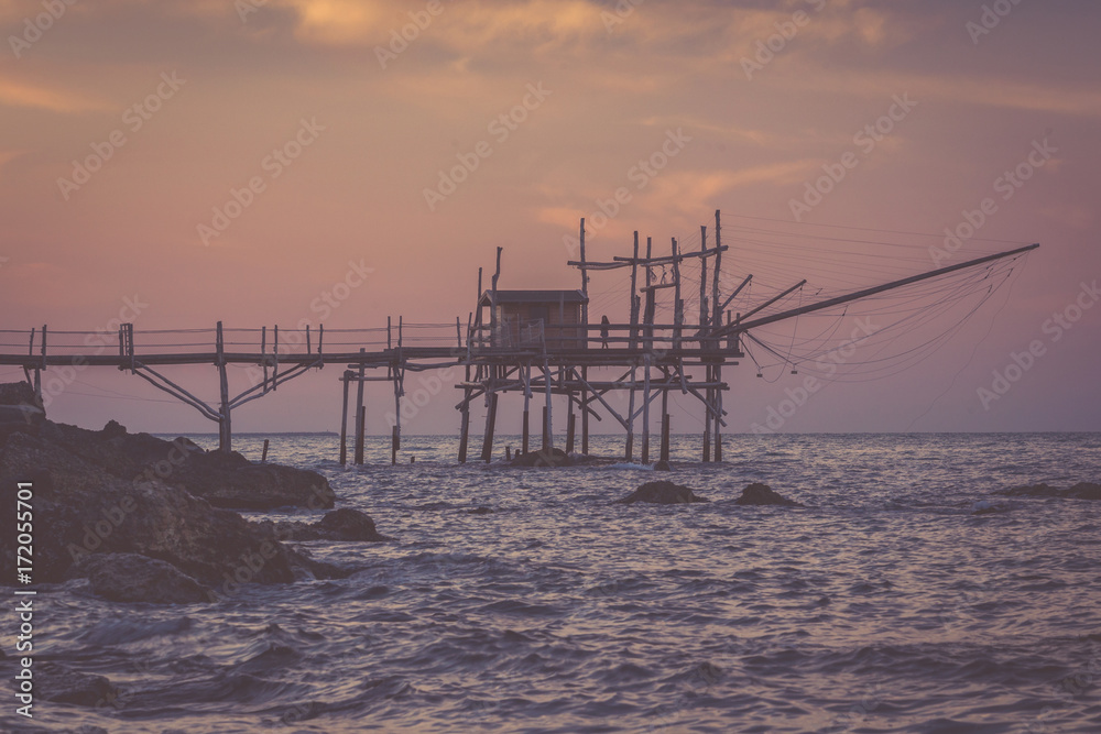 Lonely woman standing at trabocchi pier in nostalgic evening
