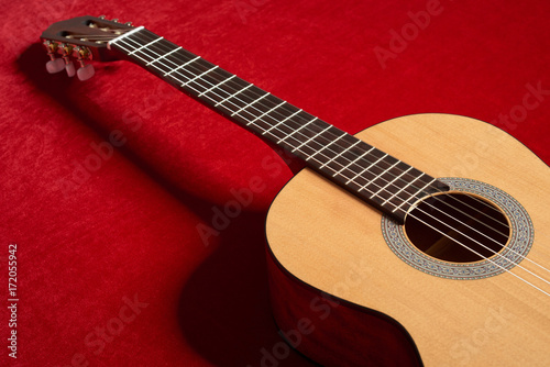 acoustic guitar on red velvet fabric, closeup object