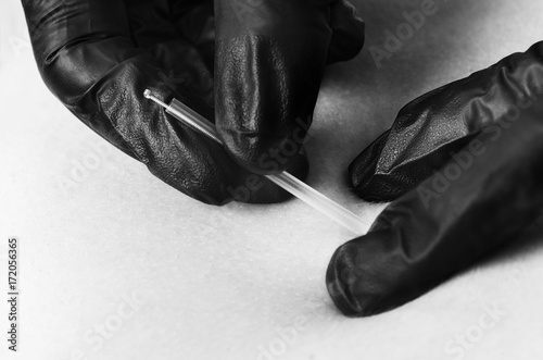Dry needling, closeup of a physiotherapist, chiropractor with a needle and black gloves in silhouette studio