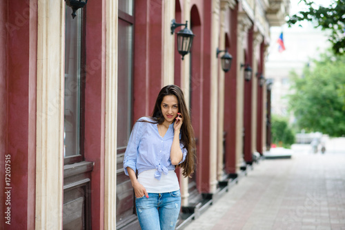 Happy and beautiful girl talking on the phone on the street.