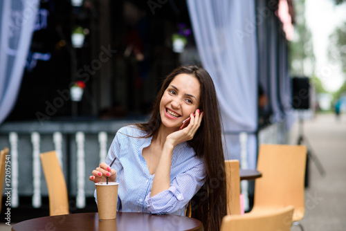 Happy and beautiful girl talking on the phone and drinking coffee.