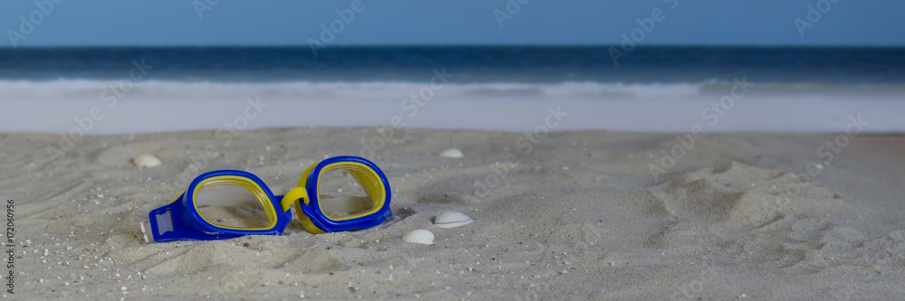 Swim goggles in the sand on the beach, panorama
