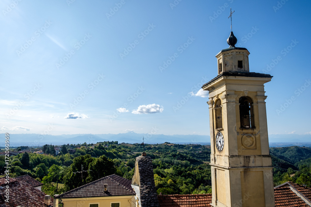 View of the central church of the town of Murazzano, in the langhe region of Piedmont, Italy. In the background, Langhe hills and italian Alps are visible.