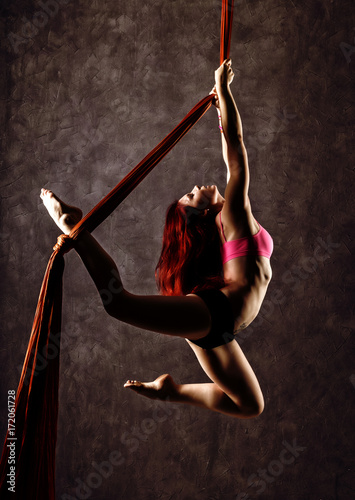 Beautiful sexy dancer on aerial silk, graceful contortion, acrobat performs a trick on a ribbons
