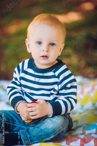 Cute child baby boy lying on blanket in summer day on nature. Happy smile, 1 year old, outdoor. Family picnic in a park.