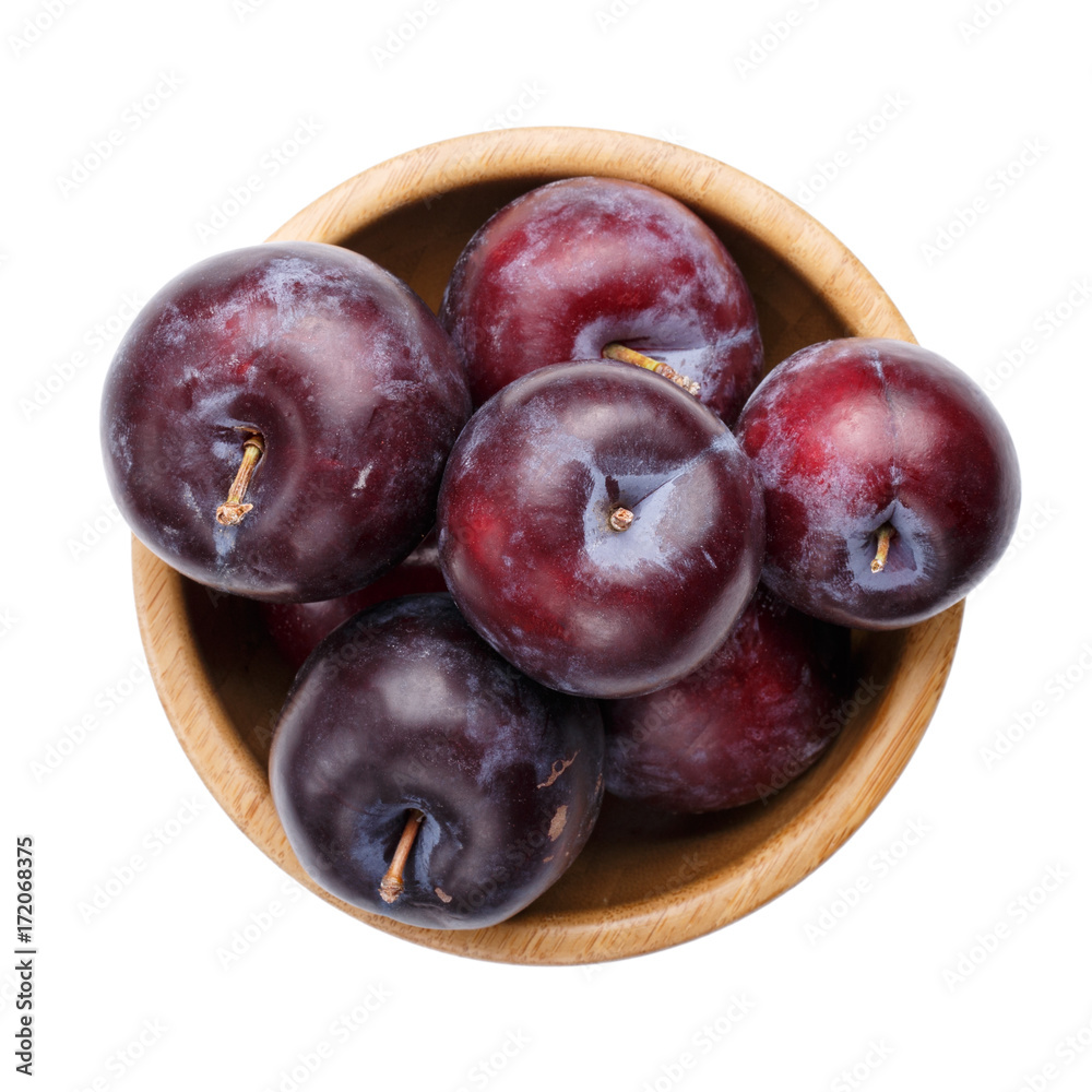 Plums in wooden bowl isolated on white background.
