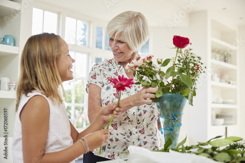 Photography Senior woman arranging flowers with granddaughter at home