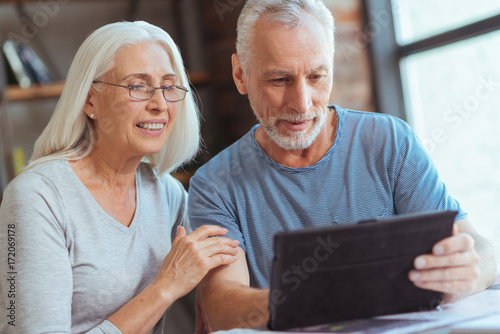 Delighted retired couple using tablet at home